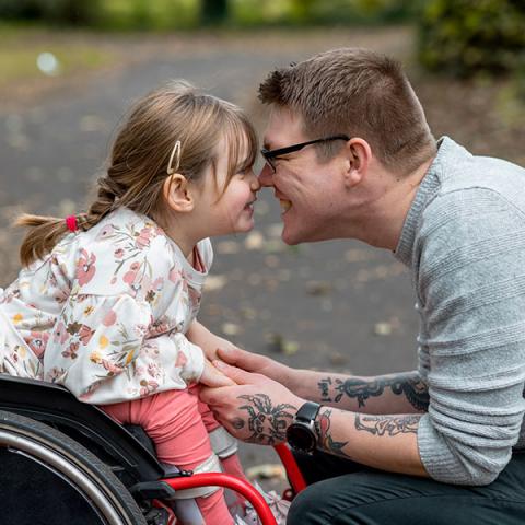 A child in a wheelchair cuddling with a parent   