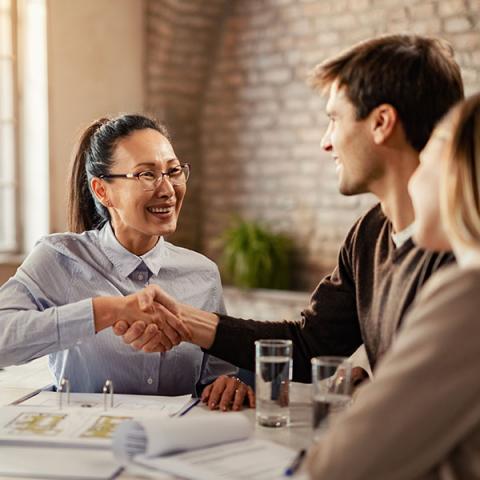 A banker shaking hands with a couple during the meeting.