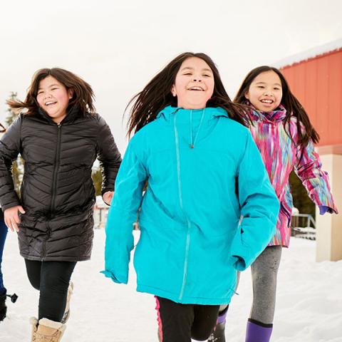 A group of happy youth running outside in the snow