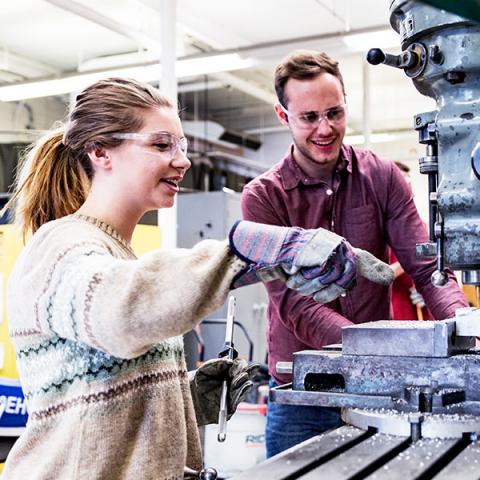 Two STEM students working together to operate a machine.