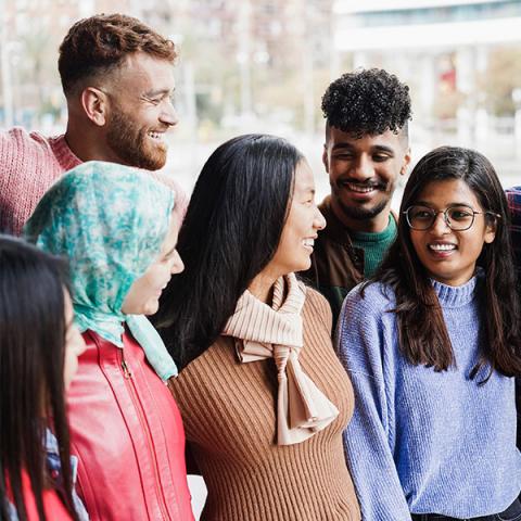 A group of young people laughing together outdoors.