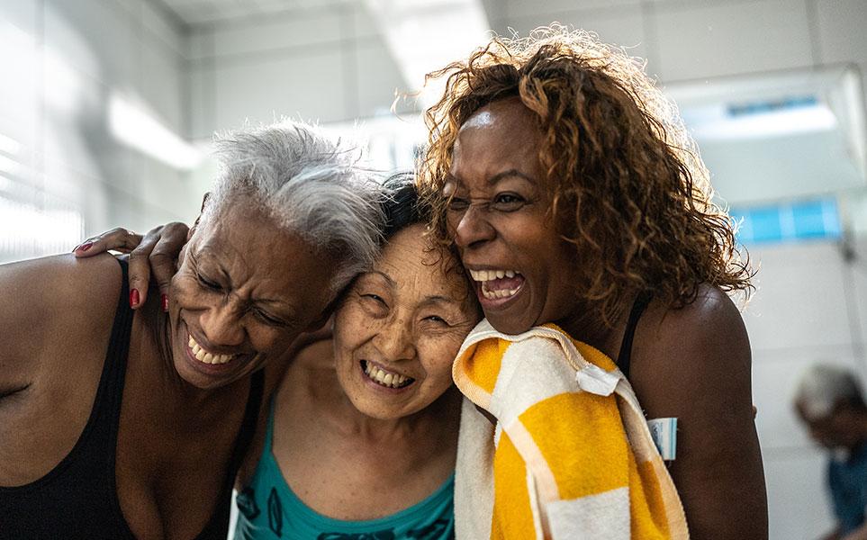 Three people hugging and laughing in the swimming pool locker room