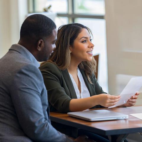 Two people are sitting at a table and reading through financial documents.