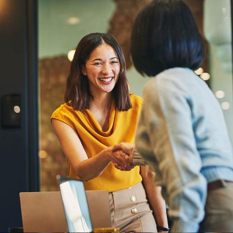 Une personne souriante serre la main de quelqu’un.