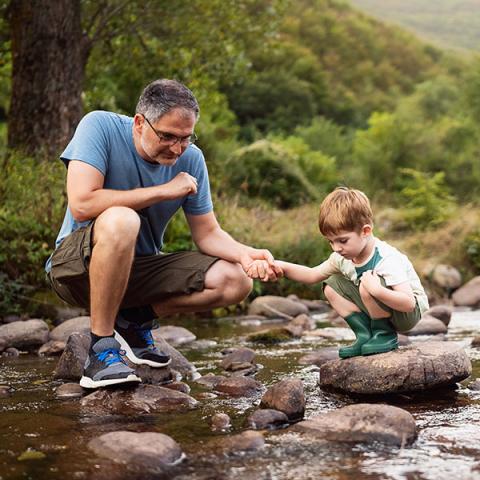 A father and son are happily exploring a river and the rocks 