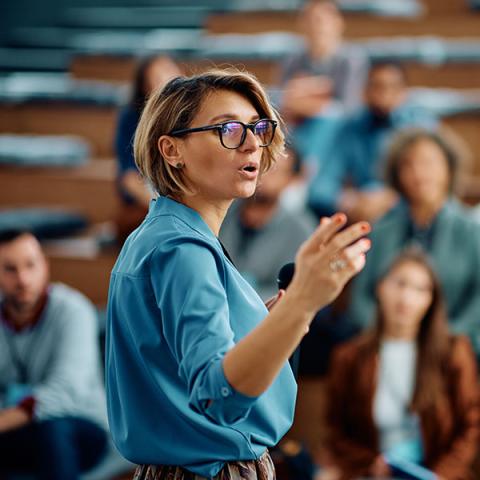 A person is talking to a large group at a conference.