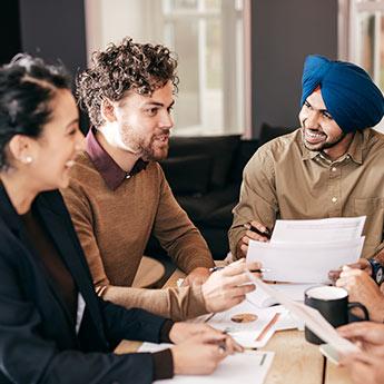 Des collègues de travail discutent amicalement autour d'une table de réunion.