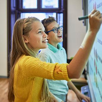 Students solve a problem on a white board.