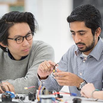 Deux hommes résolvent un problème électronique au travail.