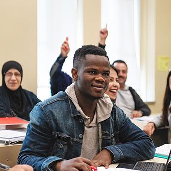 Des étudiants universitaires lèvent la main pour répondre à une question.