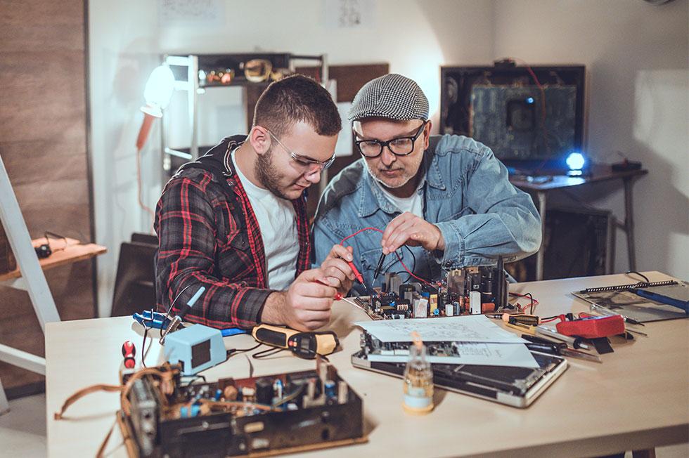 Two people working on electronics together.