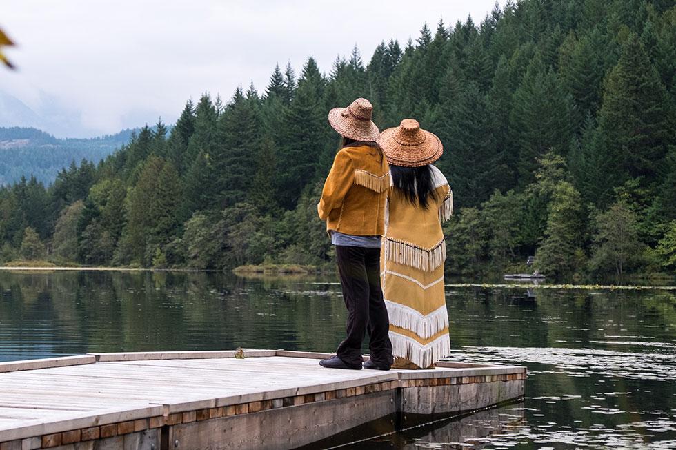 Jeunes Autochtones debout sur un quai et regardant un lac.