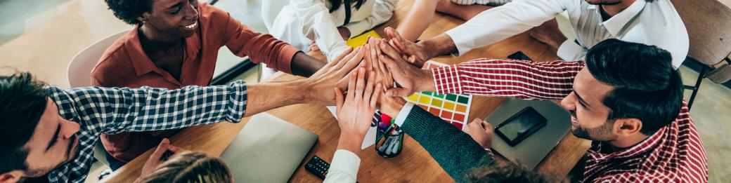 Group of people sitting at a table smiling and giving a high five.