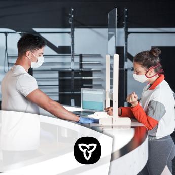 Two people standing at a reception desk who are wearing masks