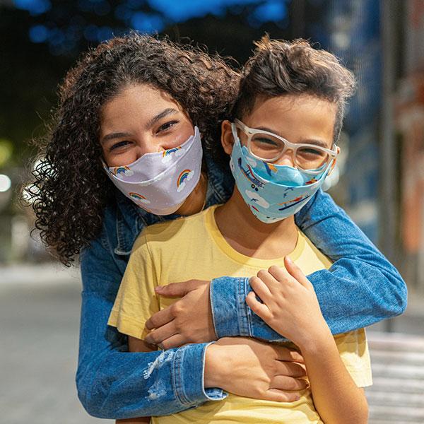 Youth wearing respiratory masks holding each other outdoors.