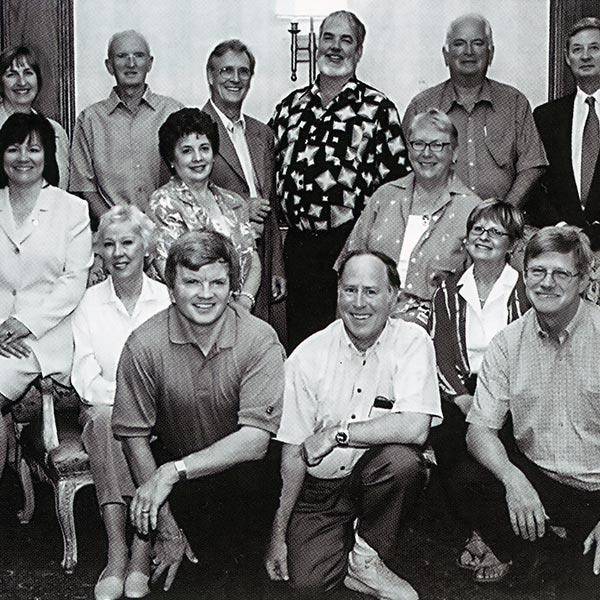 A black and white image of a group of 16 individuals, who make up the Grant review team chairs in Ontario for 2003, sit and stand for an official photo.