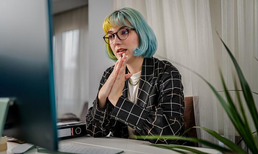 Une femme assise devant un ordinateur participe à une réunion en ligne.