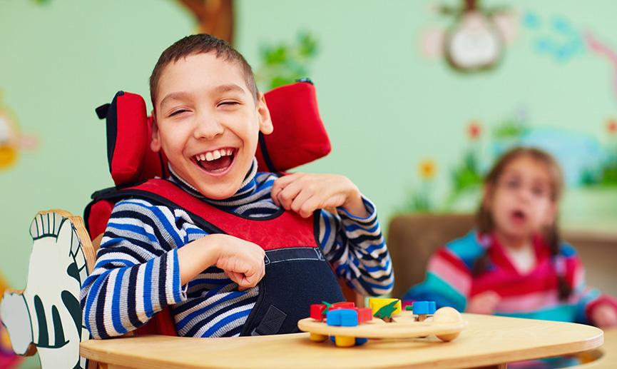 Un jeune garçon dans un fauteuil roulant rit en jouant à des jeux 