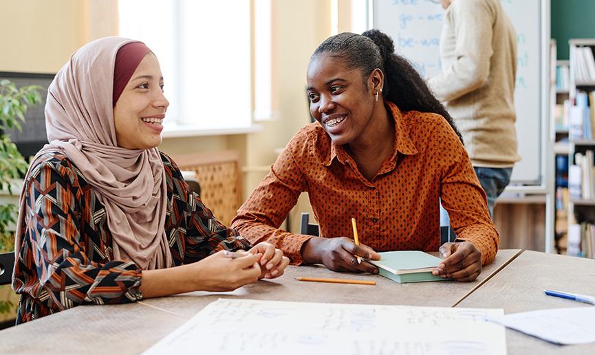 Young Black and Middle Eastern women having fun talking about something during class.