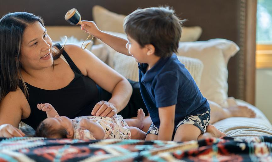 A mother plays with her two children inside their home