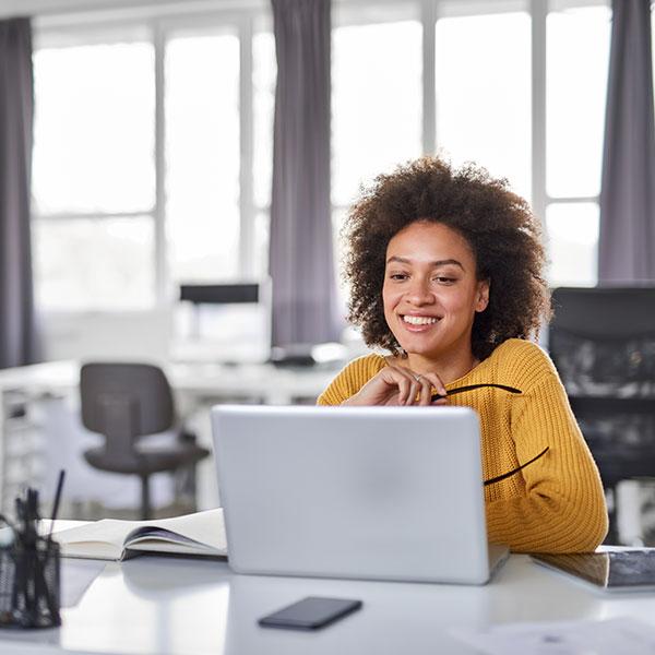 A photo a woman happily working on a computer.