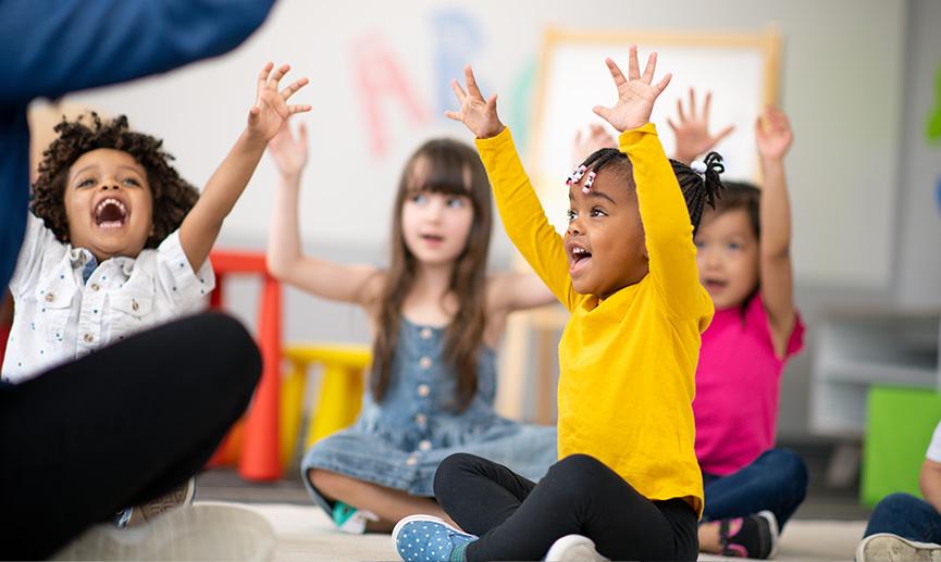 A group of happy children sitting inside a classroom