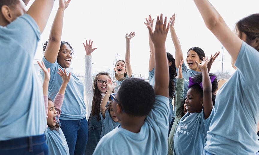 A group of volunteers cheer with their hands raised in the air.