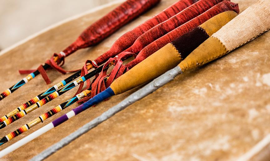 Des baguettes de tambour autochtones traditionnelles reposent sur un large tambour, prêtes pour les célébrations de pow-wow.