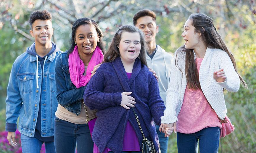 A diverse group of teenagers walk through the park.