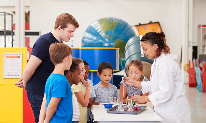 Un groupe d’étudiants debout autour d’une table apprend à partir d’une expérience scientifique.