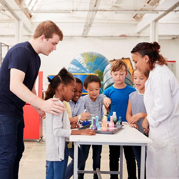 Un groupe d’étudiants debout autour d’une table apprend à partir d’une expérience scientifique.