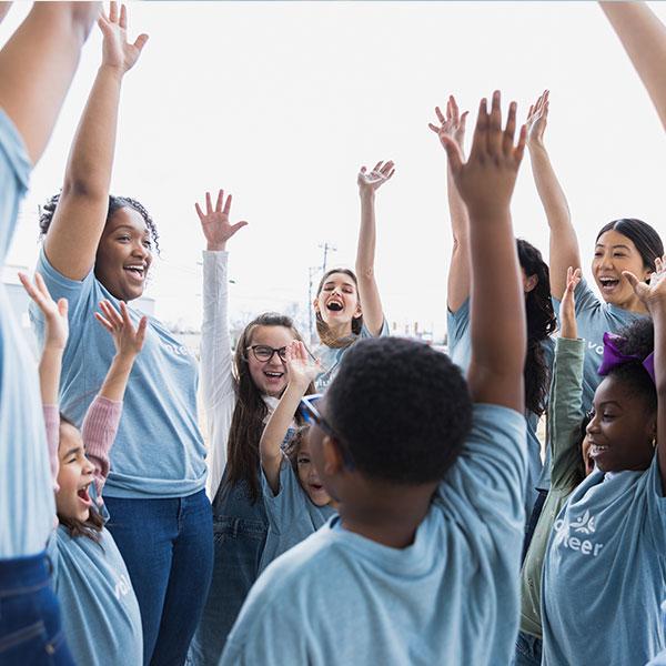 Des enfants et des jeunes leaders lancent des acclamations durant un programme en plein air.