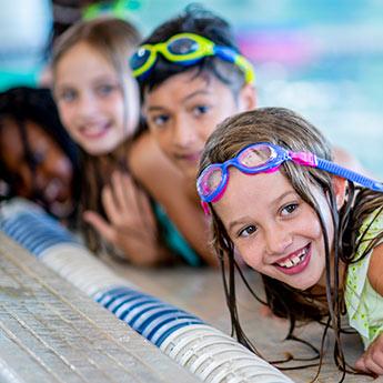 Young kids in a swimming lesson at the side of pool.