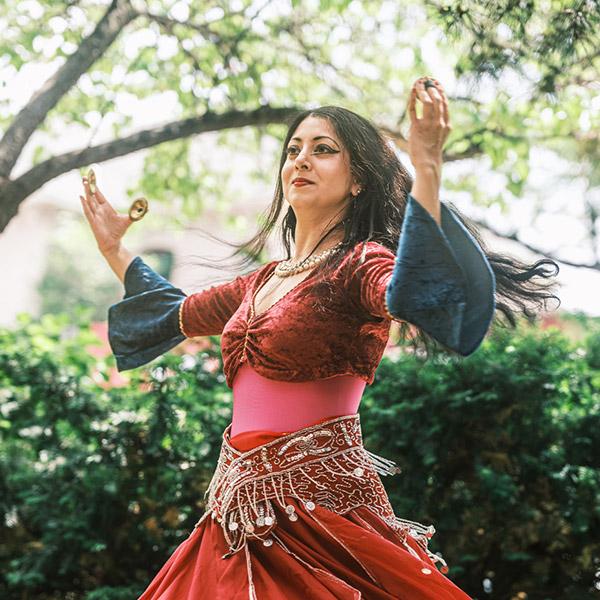 A women wearing a dress is dancing in a garden.