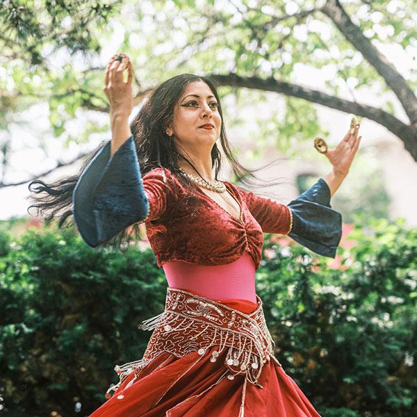 A women wearing a dress is dancing in a garden.