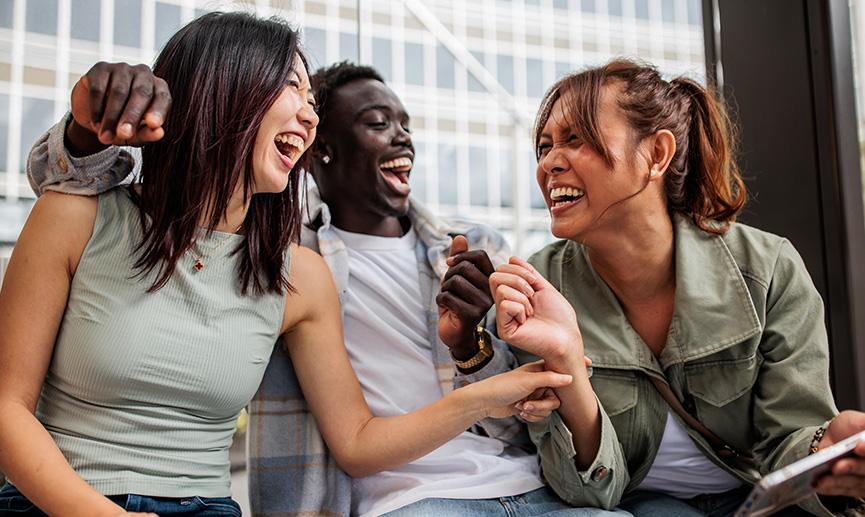 A group of friends sits together at a bus stop enjoying a fun, casual moment.