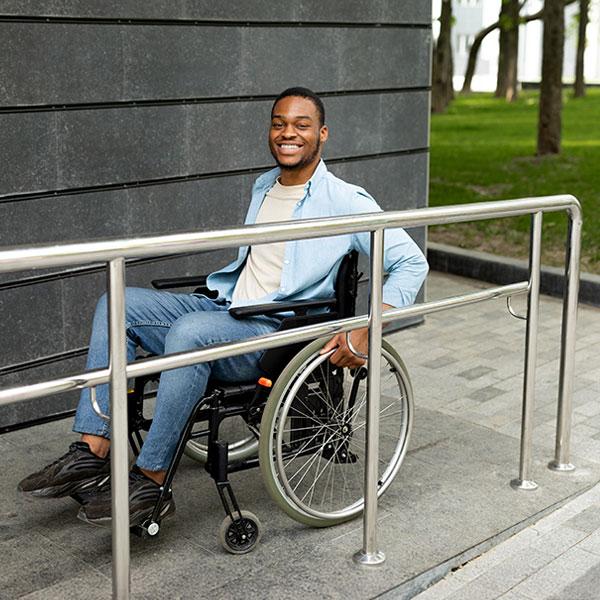 A person in a wheelchair is using an outdoor ramp into a building.