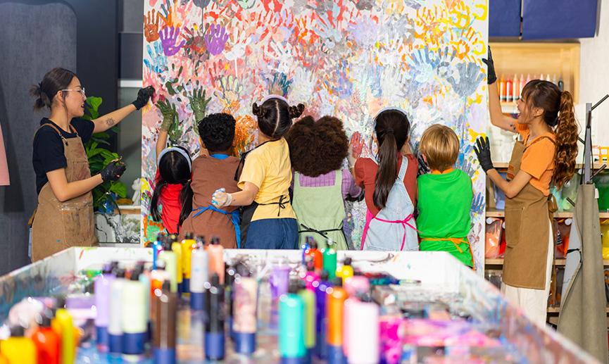 School children learning acrylic art on canvas frame workshop with teacher at art studio.