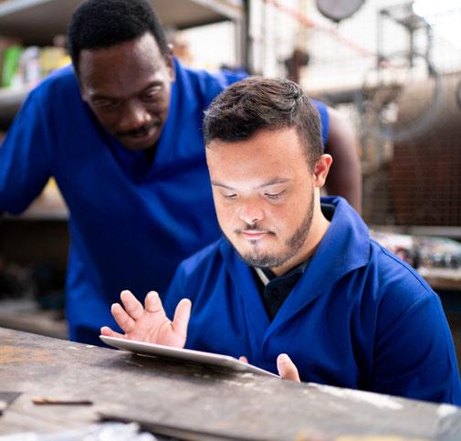   Colleagues using a digital tablet and working in a factory.