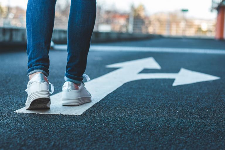 Person walking down the road on a directional arrow.