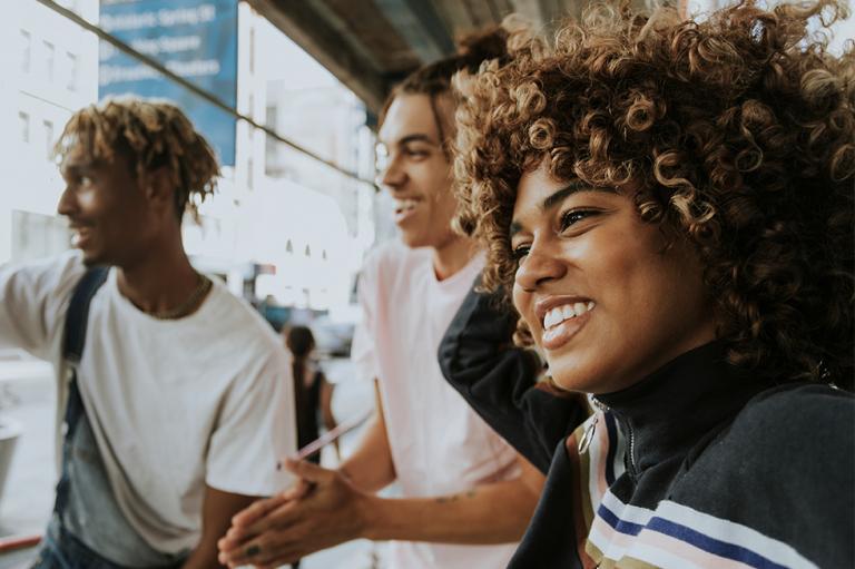 Groupe de jeunes racialisés regardant au loin et souriant.