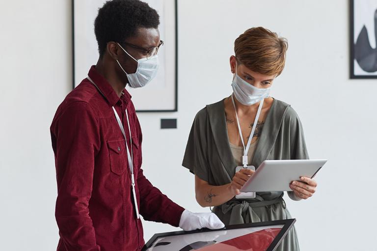 Deux personnes portant des masques dans une galerie d’art.