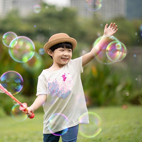 Young child plays with bubbles outside in a park