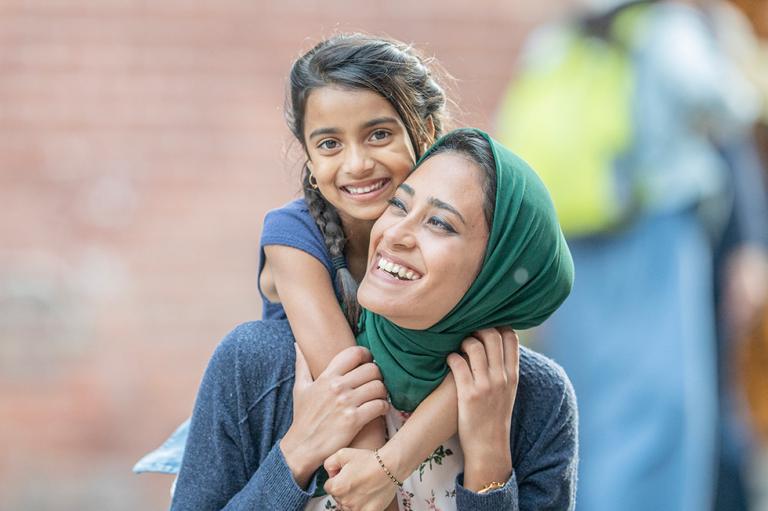 Mother and daughter hugging and laughing outdoors