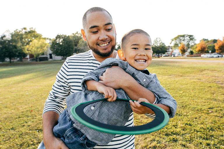 A father and son playing frisbee in the park.