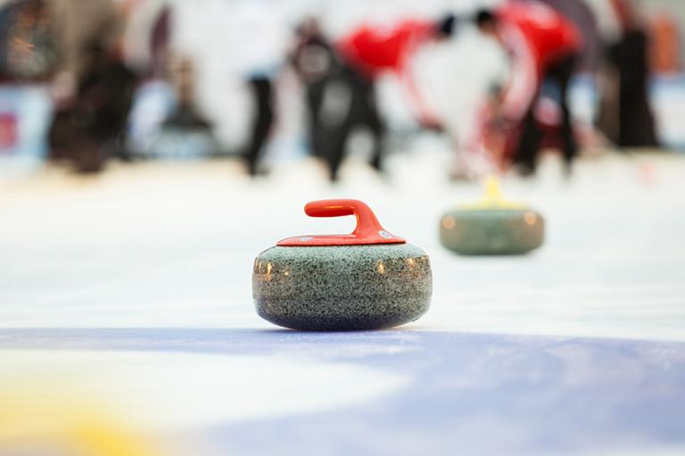 A close up of a curling rock on a curling rink.
