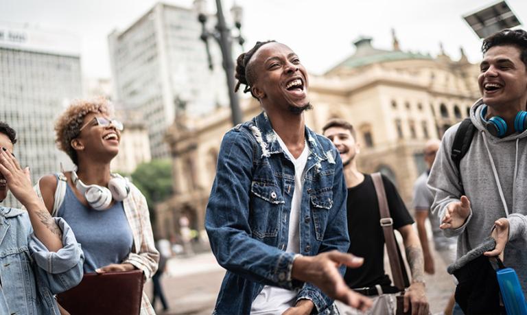 A group of friends talking and dancing in the street.