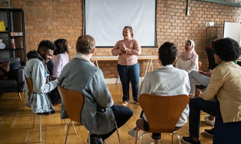 Jeune femme ayant des besoins particuliers qui s’adresse à un groupe.